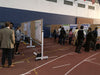 People visiting a science fair with posters on display in an indoor sports facility.